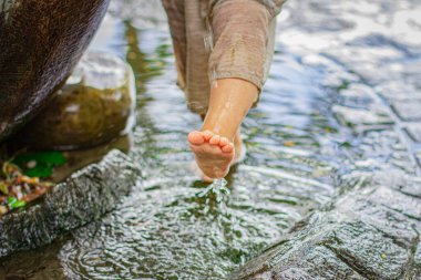Küçük çocukların ayağı suyun içinde. Çocuk bir çeşmede sokakta yıkanır. 