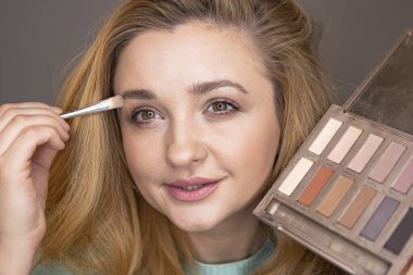 Genç kadın makyaj yapıyor. Makyaj blogcusu kamera önünde dekoratif kozmetik testleri yapıyor