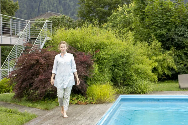 快乐的女人正在房子院子里的游泳池边休息 — 图库照片