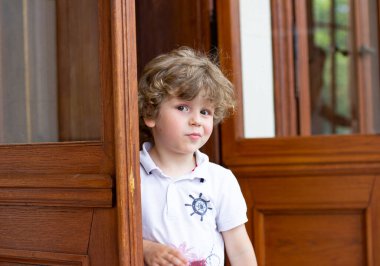 Küçük çocuk kapının arkasında saklanıyor.