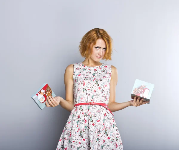 Piękna rudowłosa dziewczyna z świąteczny prezent w jego ręce. portret szczupła i piękna dziewczyna na szarym tle — Zdjęcie stockowe