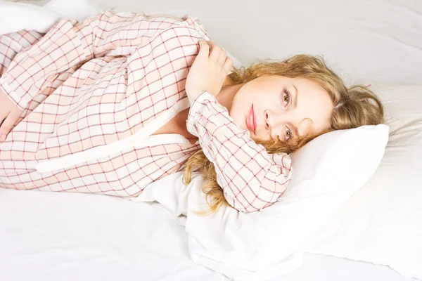 Jonge zwangere vrouw luxuriates in een witte bed. — Stockfoto