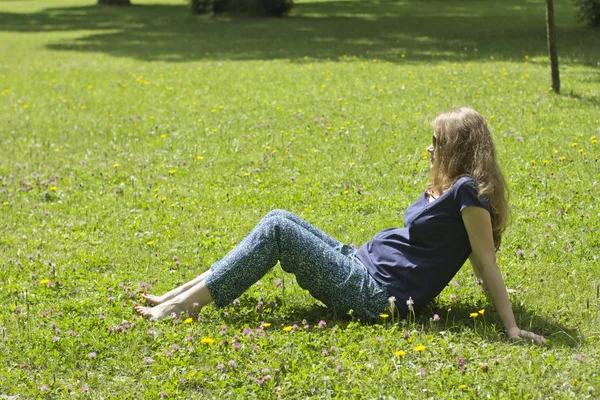 Beautiful pregnant blonde lying on green grass. Portrait of pregnant woman. Outdoors — Stock Photo, Image