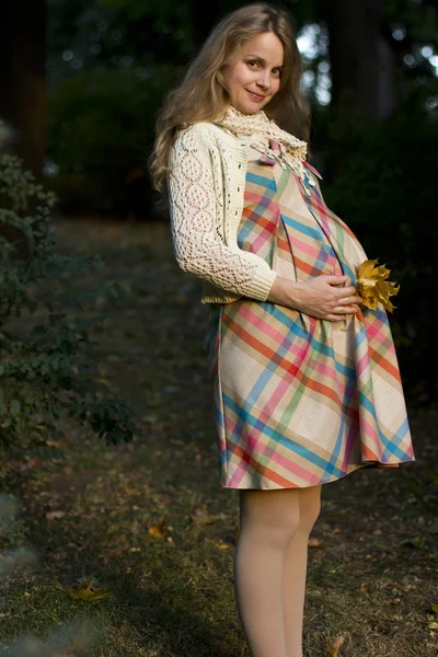 Schöne, fröhliche schwangere Blondine spaziert durch den Park. Porträt einer jungen Schwangeren — Stockfoto