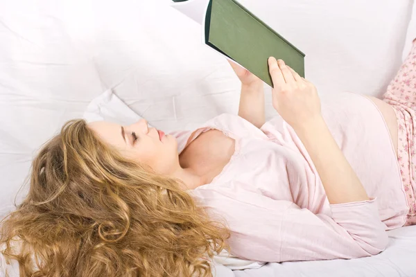 Hermosa rubia embarazada leyendo un libro en la cama. Retrato de la mujer embarazada — Foto de Stock