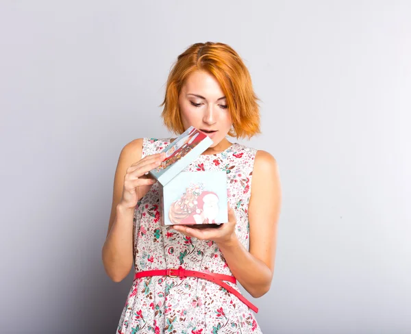Vakker rødhåret jente med gaveeske i hånden. Portrett av en vakker ung pike i kort kjole – stockfoto
