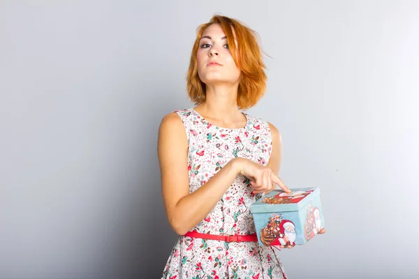 Menina ruiva bonita com caixa de presente nas mãos. Retrato de menina bonita em um vestido curto — Fotografia de Stock