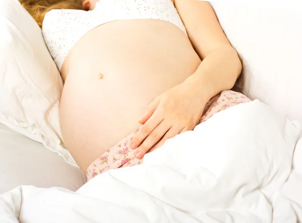 Jovem mulher grávida luxates em uma cama branca.Mulher Cama Portrait.Beautiful grávida encaracolado loira — Fotografia de Stock