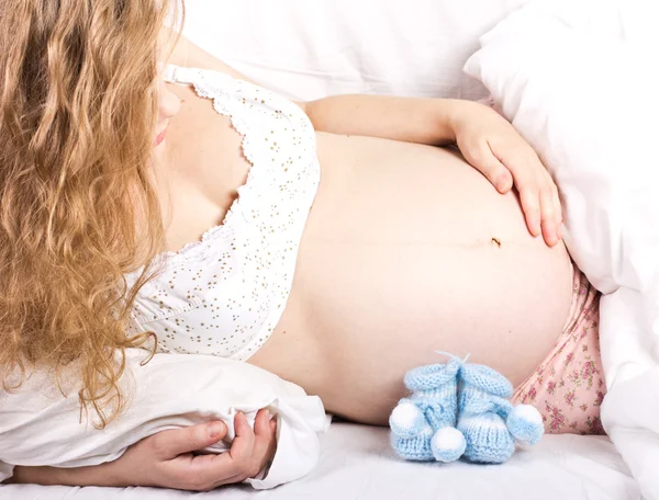 Beautiful pregnant blonde woman with booties in her hand — Stock Photo, Image