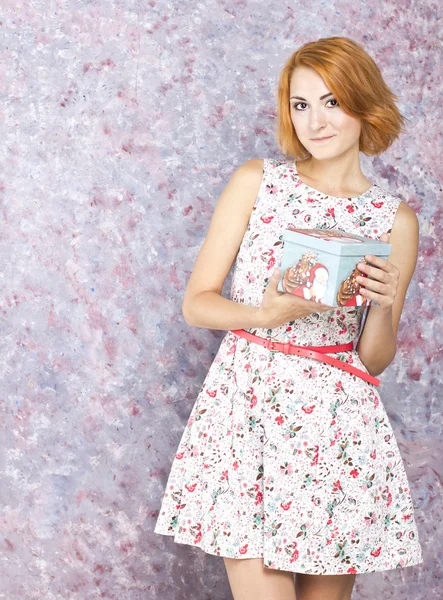 Kısa bir elbise hediye kutusu tutan ince kız güzel. Renkli arka plan. Kızıl saçlı kız portresi — Stok fotoğraf