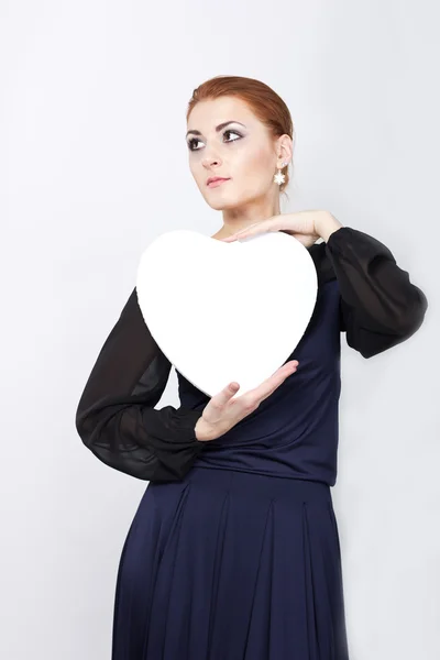 Hermosa chica delgada en vestido de noche con un gran corazón blanco. Retrato de niña pelirroja — Foto de Stock