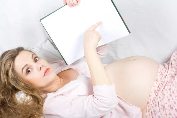 Beautiful pregnant blonde reading a book in bed. Portrait of pregnant woman — Stock Photo, Image