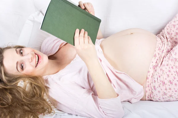Vacker gravid blondin läser en bok i sängen. Porträtt av gravid kvinna — Stockfoto