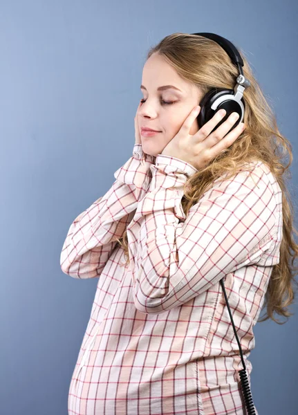Smuk gravid blondine lytter til klassisk musik på hovedtelefoner. Portræt af gravid kvinde. Udviklingen af barnet i livmoderen - Stock-foto