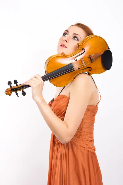 Молода руда дівчина зі скрипкою в руках на білому тлі.початок сукні. Довга помаранчева сукня — стокове фото