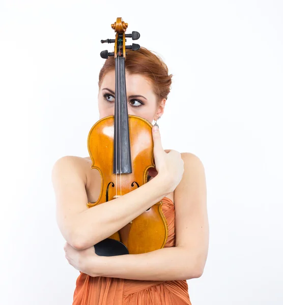 Jeune fille aux cheveux roux avec un violon dans les mains sur un fond blanc. Robe de soirée. Longue robe orange. — Photo