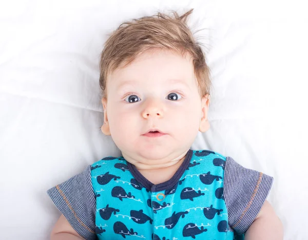 Ritratto di un bambino sorridente. Un bambino su un letto bianco. Bello ragazzo . — Foto Stock