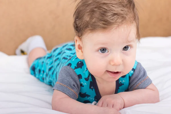 Ritratto di un bambino sorridente. Un bambino su un letto bianco. Bello ragazzo . — Foto Stock