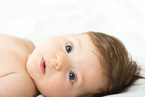 Portret van een naakte kind. Een kind op een witte bed. Knappe jongen. glimlachend kind — Stockfoto