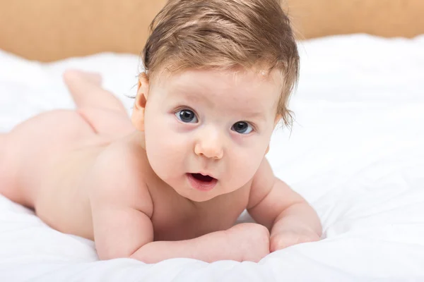 Portrait of a naked child. A child on a white bed. Handsome boy. smiling child Stock Photo