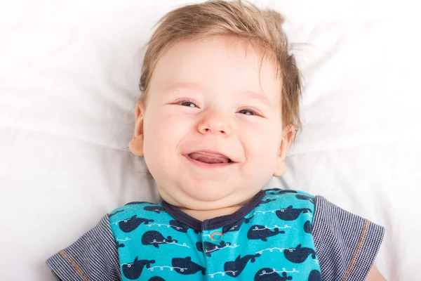 Ritratto di un bambino sorridente. Un bambino su un letto bianco. Bello ragazzo . — Foto Stock