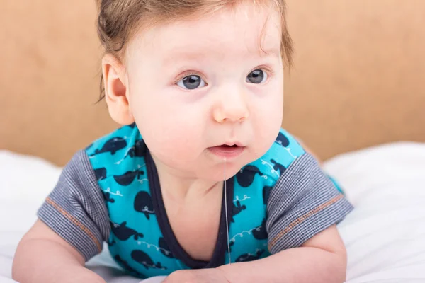 Portret van een glimlachend kind. Een kind op een witte bed. Knappe jongen. — Stockfoto