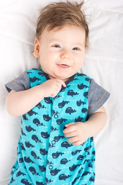 Retrato de uma criança sorridente. Uma criança numa cama branca. Rapaz bonito . — Fotografia de Stock