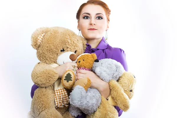 Chica joven con un montón de animales de peluche. Chica con juguetes suaves sobre un fondo blanco — Foto de Stock
