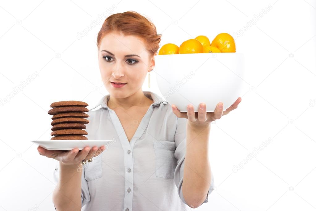 Young slim girl with tangerines and chocolate chip cookies. Portrait of a woman on a diet. Tasty and useful. Counting calories. Portrait of a girl isolated on a white