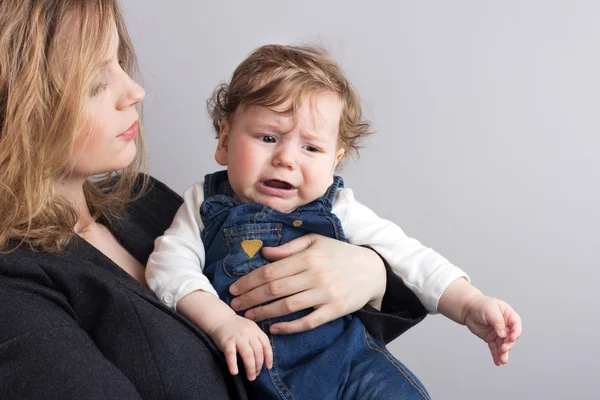 Il bambino piange sulle braccia della madre.Ritratto di madre e figlio. bambino maudlin — Foto Stock