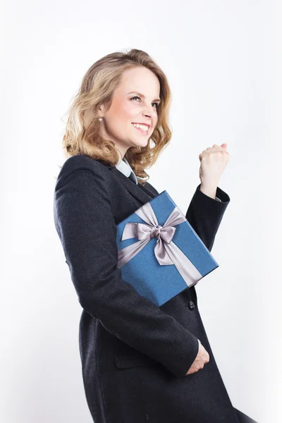 Happy affärskvinna med en gåva. Porträtt av en blondin i en jacka på en vit — Stockfoto