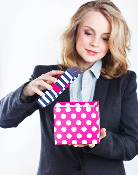 Beautiful blonde in a strict jacket with colorful gift box. — Stock Photo, Image