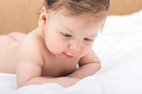 Portret van een naakte kind. Een kind op een witte bed. Knappe jongen. glimlachend kind — Stockfoto