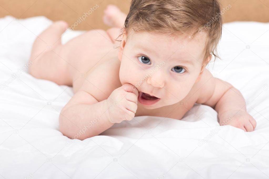 Portrait of a naked child. A child on a white bed. Handsome boy. smiling child