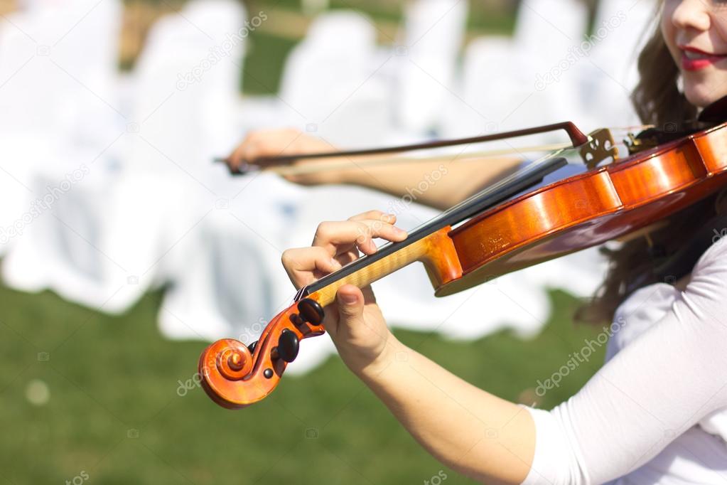 Girl playing on the violin outdoors. Musician for the wedding.Violin under the open sky