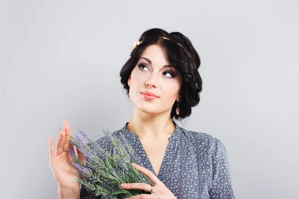 Beautiful brunette with a sprig of lavender. Portrait of a young girl on a gray background. The brunette with the Greek haircut — Stock Photo, Image