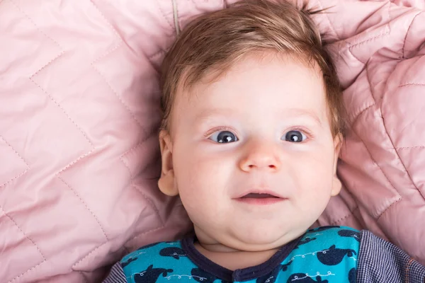 Bébé mignon dans un lit rose. Portrait d'un bébé. Portrait d'un enfant souriant. Un enfant sur un lit blanc. Beau garçon . — Photo