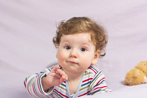 Hermoso niño en cuna con juguetes. Lindo chico. Rubia rizada. Retrato de un bebé — Foto de Stock