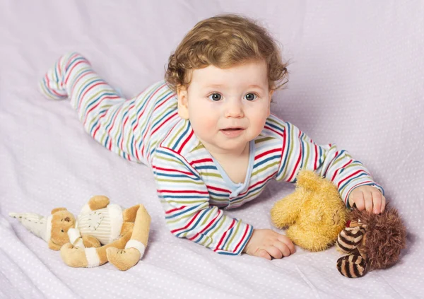 Hermoso niño en cuna con juguetes. Lindo chico. Rubia rizada. Retrato de un bebé — Foto de Stock