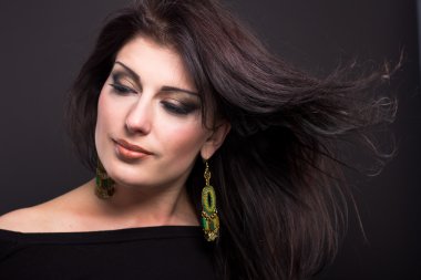 Güzel esmer siyah arka plan üzerinde uçan bir saçlı. Sağlıklı saçlar. Saç modeli.