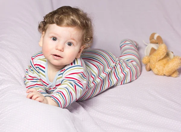 Bela criança no berço com brinquedos. Rapaz giro. Loura encaracolada. Retrato de um bebê — Fotografia de Stock