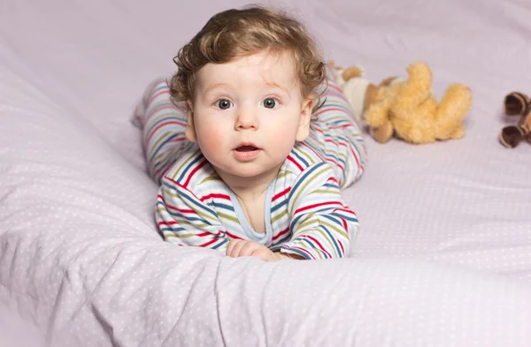 Piękne dziecko w łóżeczku z zabawkami. Ładny chłopak. Kręcone blond. Portret dziecka — Zdjęcie stockowe