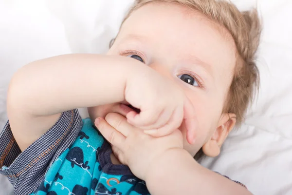 Portret van een glimlachend kind. Een kind op een witte bed. Knappe jongen. — Stockfoto