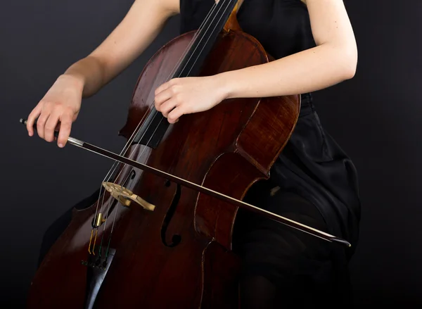 A young girl plays the cello in the dark. Hands on cello — Stock Photo, Image