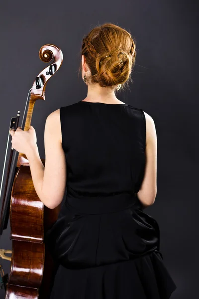 Une jeune fille joue du violoncelle dans le noir. Main sur le violoncelle — Photo