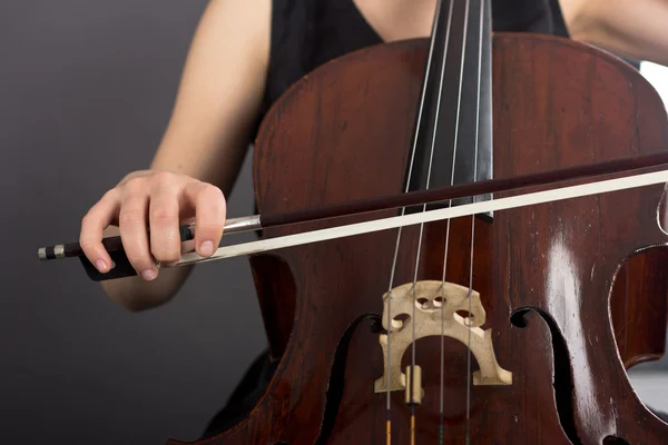 Ein junges Mädchen spielt im Dunkeln Cello. Hände am Cello — Stockfoto