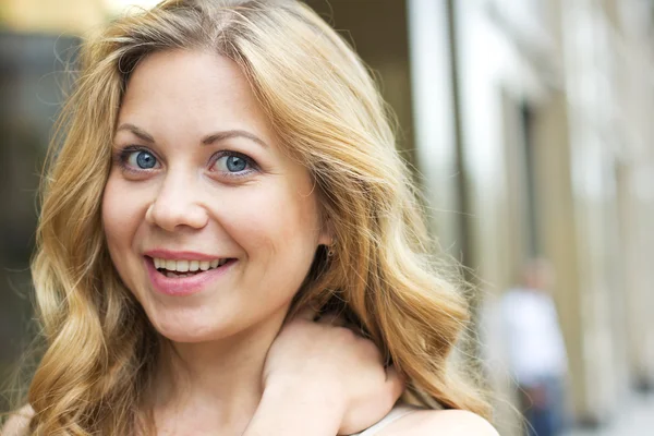 Hermosa chica rubia sonriente afuera en la calle. Retrato de una joven rizada . —  Fotos de Stock