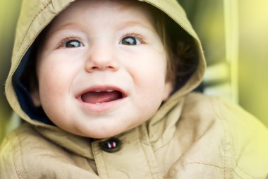 The cheerful child on a walk. Portrait of a baby in a jacket