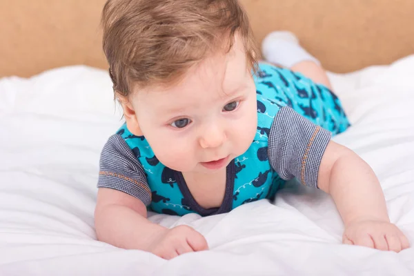 Retrato de un niño sonriente. Un niño en una cama blanca. Chico guapo . — Foto de Stock