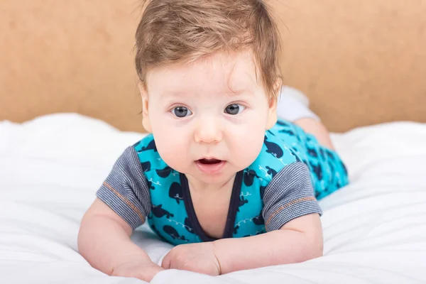 Portret van een glimlachend kind. Een kind op een witte bed. Knappe jongen. — Stockfoto